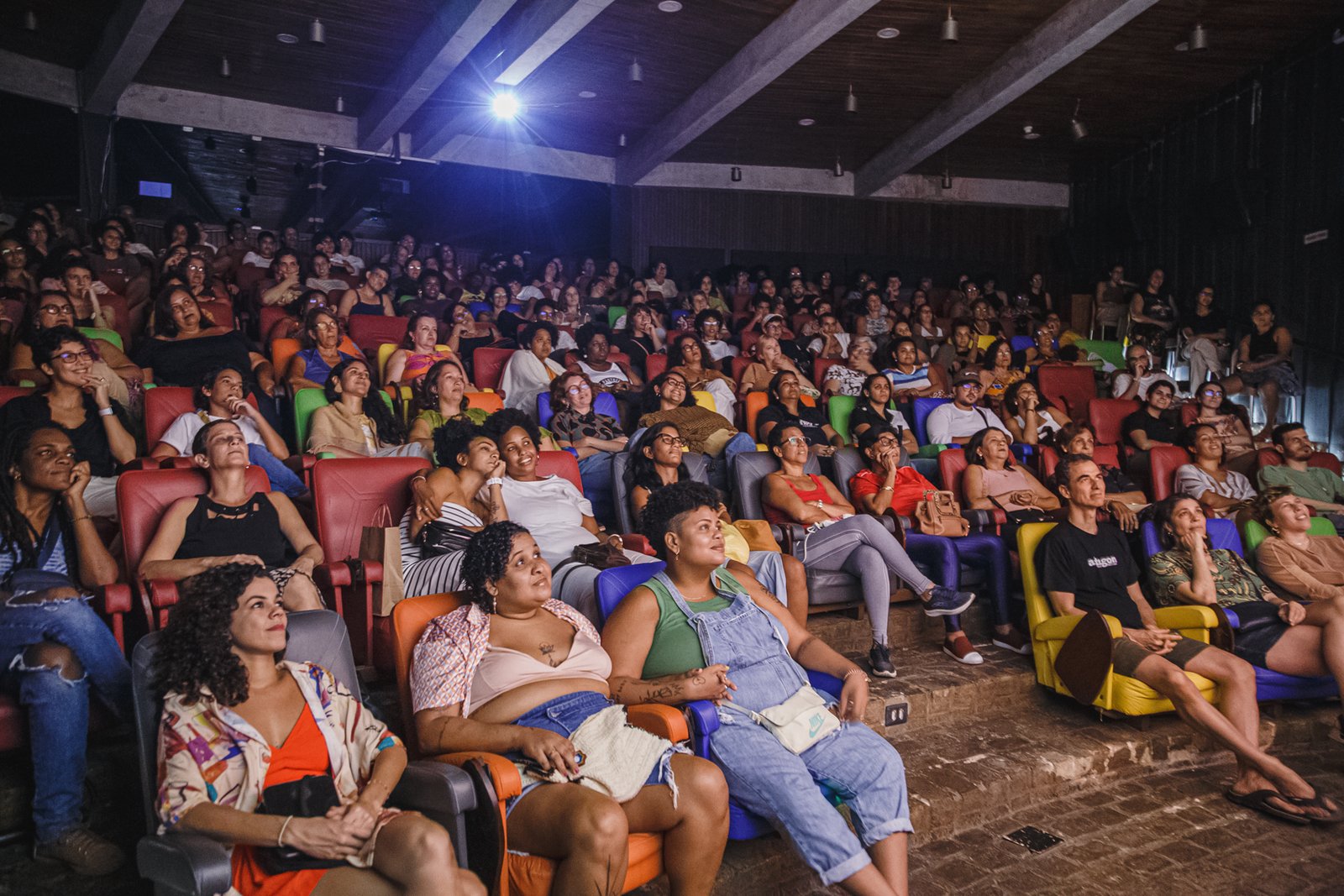 Sala de cinema lotada com pessoas que olham em direção à tela